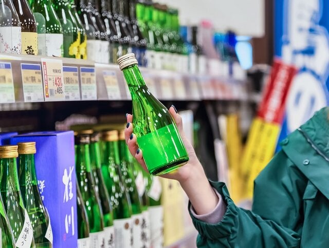 スーパーで日本酒を買う若い女性